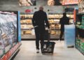 mangiare con pochi soldi Spesa in un supermercato di una grande città: carrello con pochi prodotti davanti agli scaffali alimentari