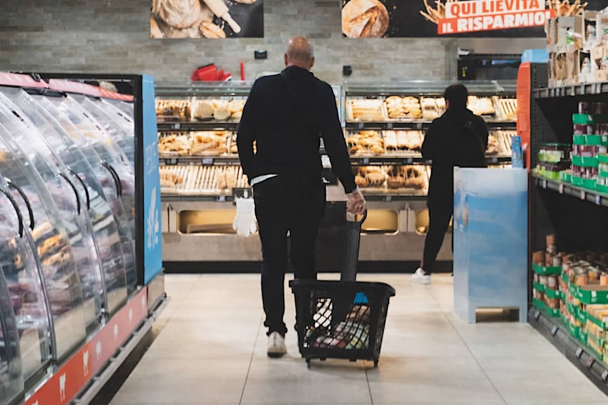 mangiare con pochi soldi Spesa in un supermercato di una grande città: carrello con pochi prodotti davanti agli scaffali alimentari